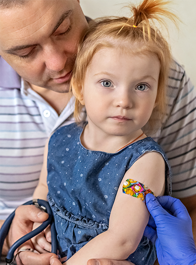 Little girl with a colourful bandage on her arm being comforted by a parent after vaccination at Botanic Ridge Doctors