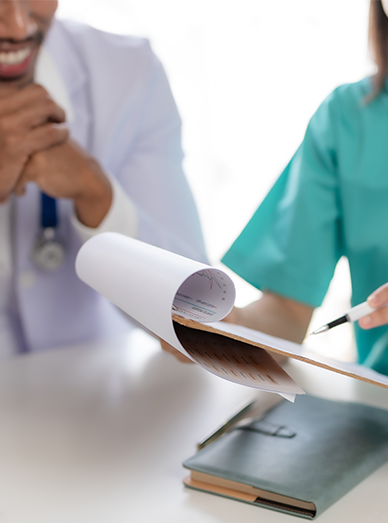 Doctor and nurse discussing a patient file with notes and reports at Botanic Ridge Doctors