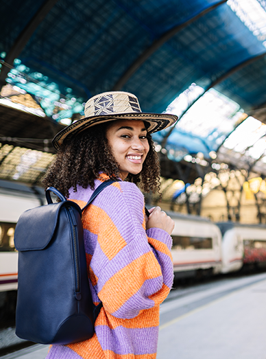 Smiling traveller with backpack standing on a train platform before a trip at Botanic Ridge Doctors
